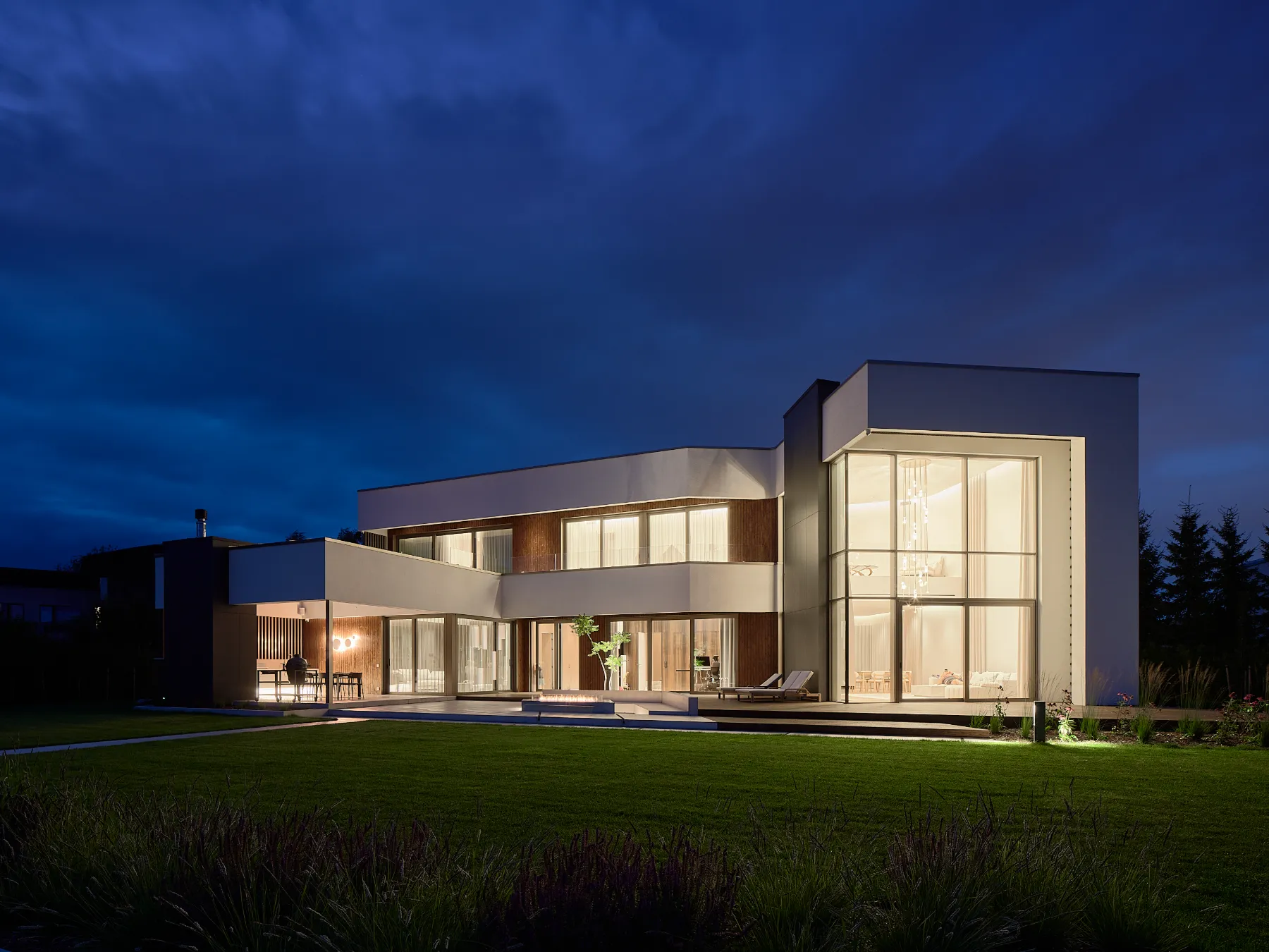 Private villa in Tallinn at dusk, the Cluster chandelier visible through the glazing