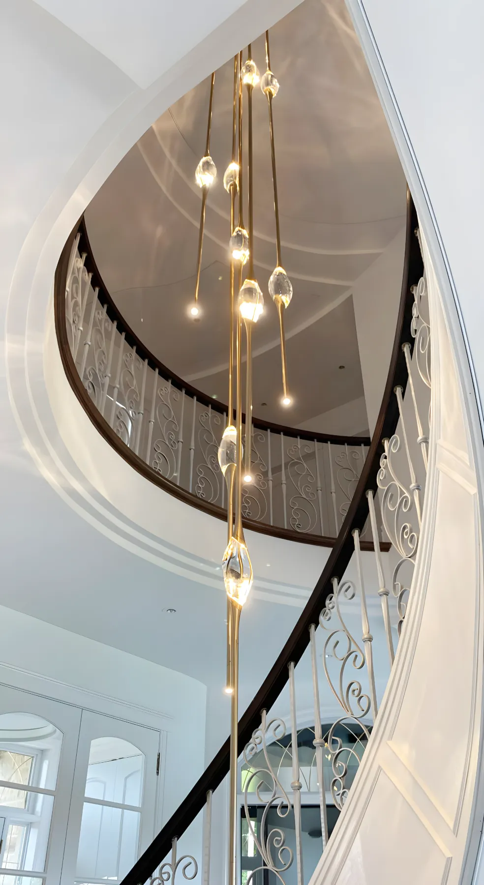 Cluster chandelier descending a spiral staircase in a private residence in Laval, Canada